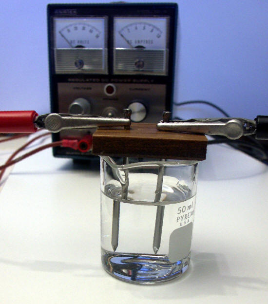 xperimental set-up containing a DC power supply plus two steel nails partially immersed in a dilute saline solution and connected to the positive (left) and negative (right) posts of the DC supply
